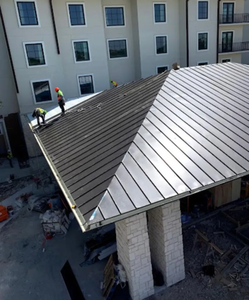 Crew installing standing seam metal roof panels on a commercial project in Ilchester